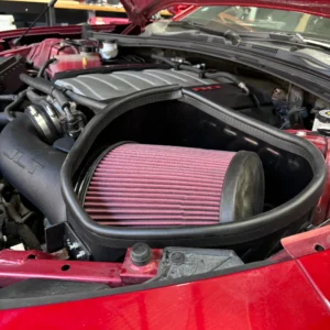 Close-up of a car engine air filter in a red vehicle.