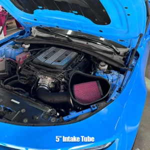 Close-up of a blue car's engine bay with a 5-inch intake tube and a pink air filter.