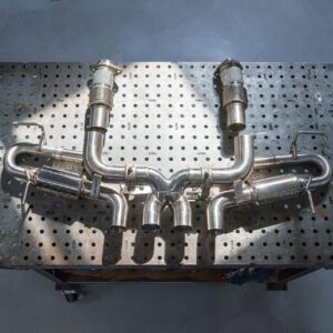 Custom stainless steel exhaust manifold on a workbench.